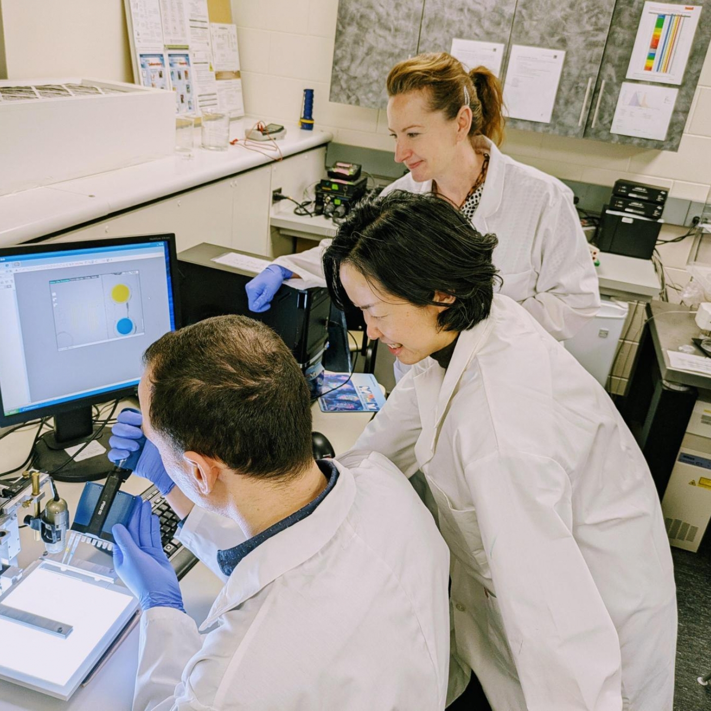 Three researchers in white labcoats.