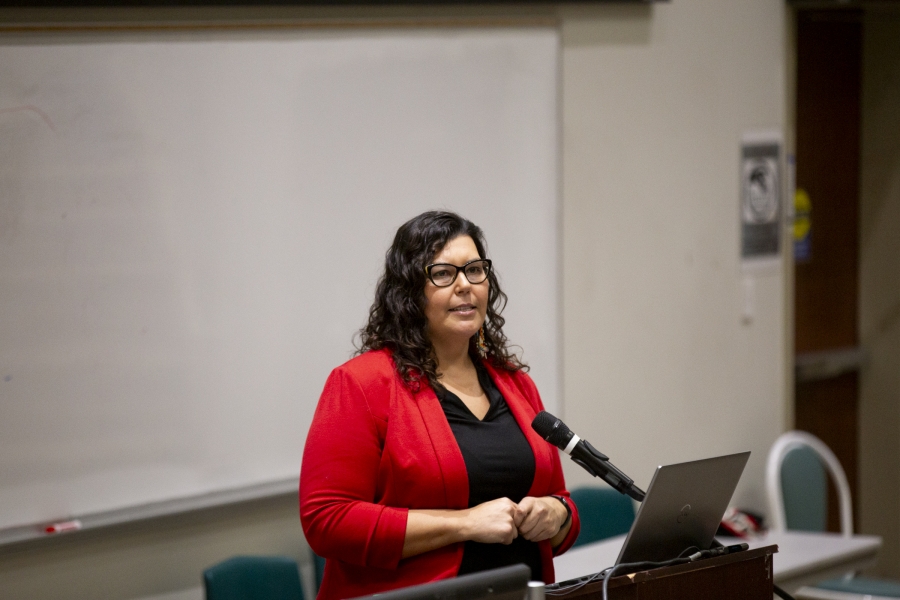 Dr. Marcia Anderson standing in front of a podium wearing a red suit