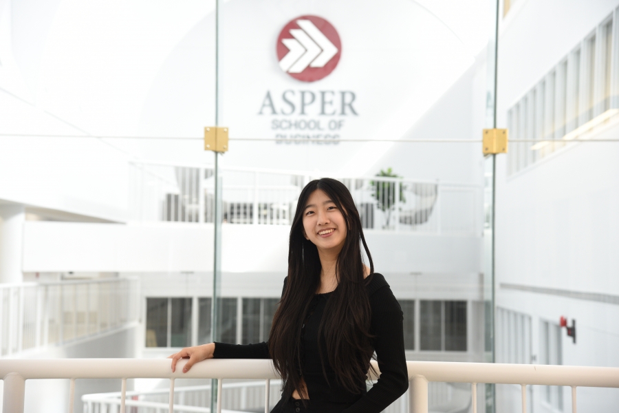 Jaehyun Woo stands in front of Asper School of Business signage