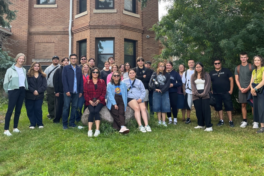 Student group poses outdoors by a building.