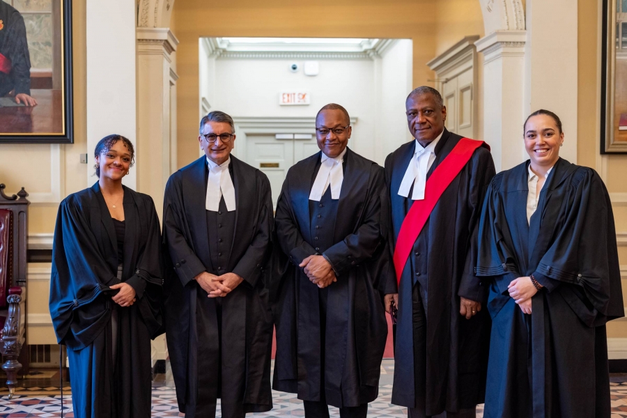 Two students stand alongside three judges, all robed