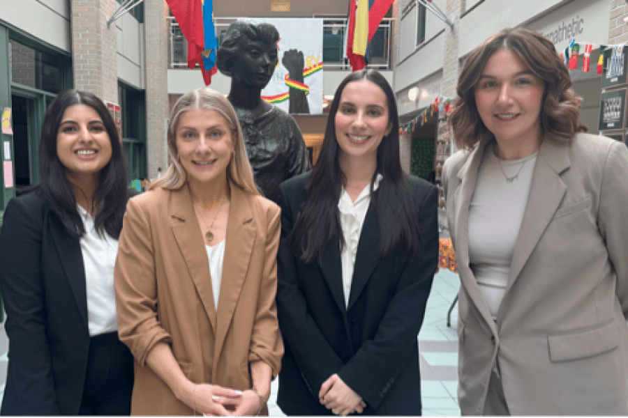 four business law students in suits stand in the main hallway of Balmoral Hall