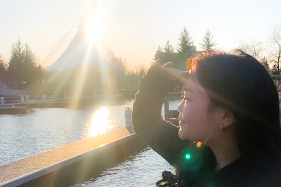 A person looking out over a body of water with a sunset behind a large tent in the background.