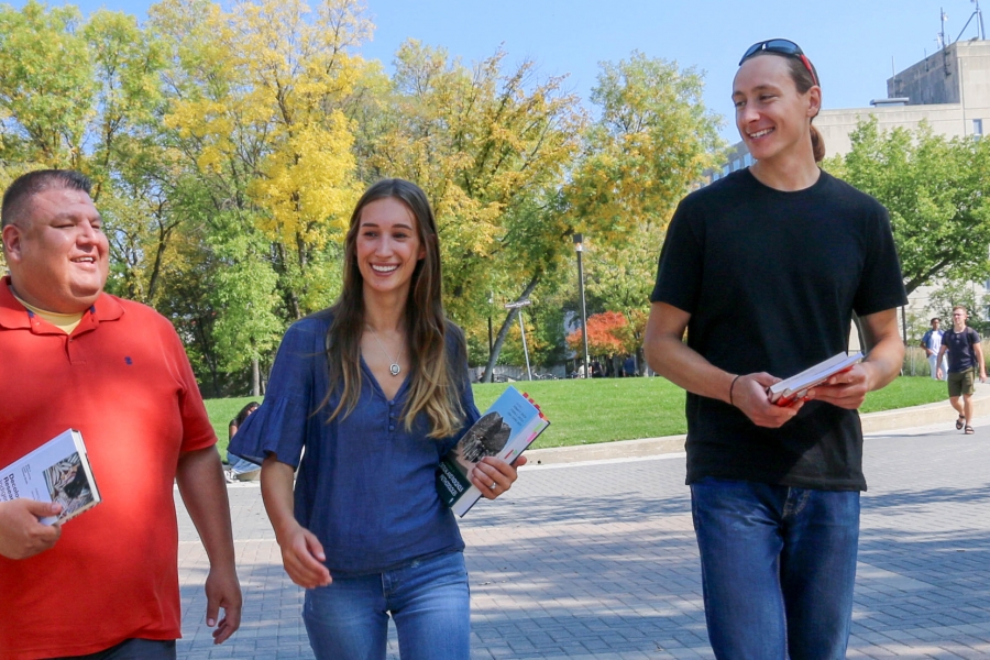Two men and a woman walk across the UM campus.