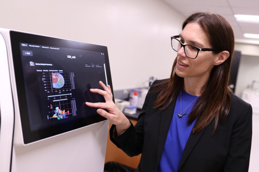 Dr. Britt Drögemöller presses a touchscreen on a large machine used for research.