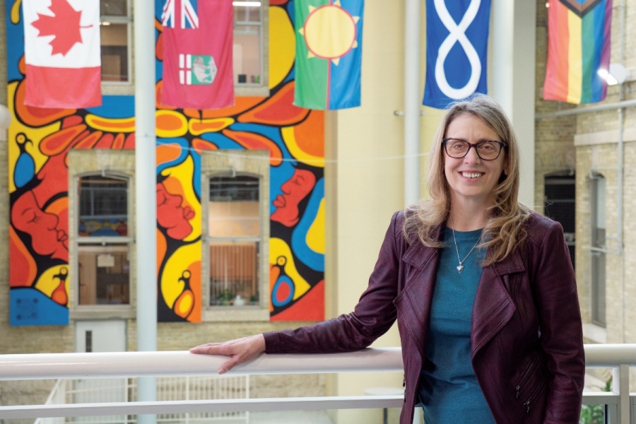 A person smiling, behind her are flags hung from the ceiling.