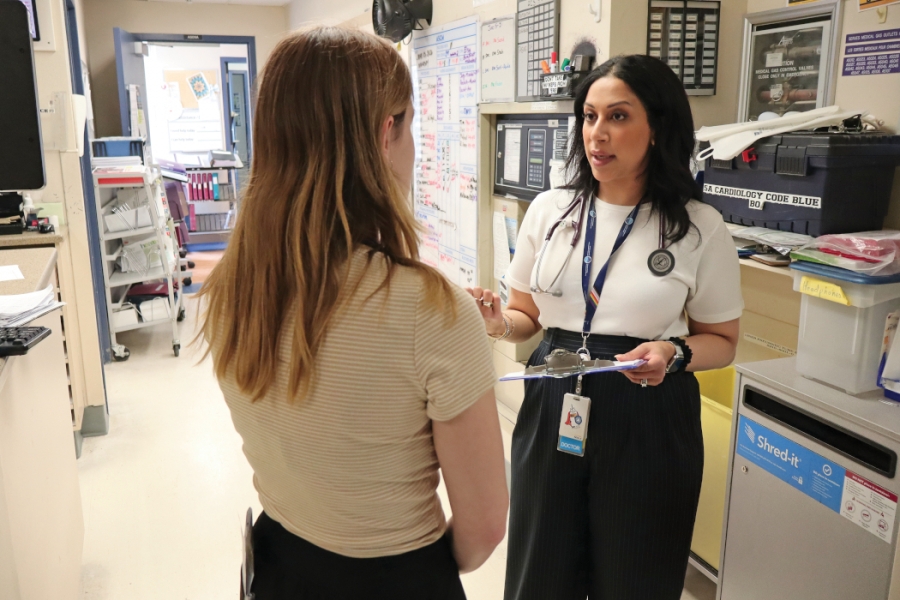 Dr. Mahwash Saeed speaks with a medical student in a hospital hallway.