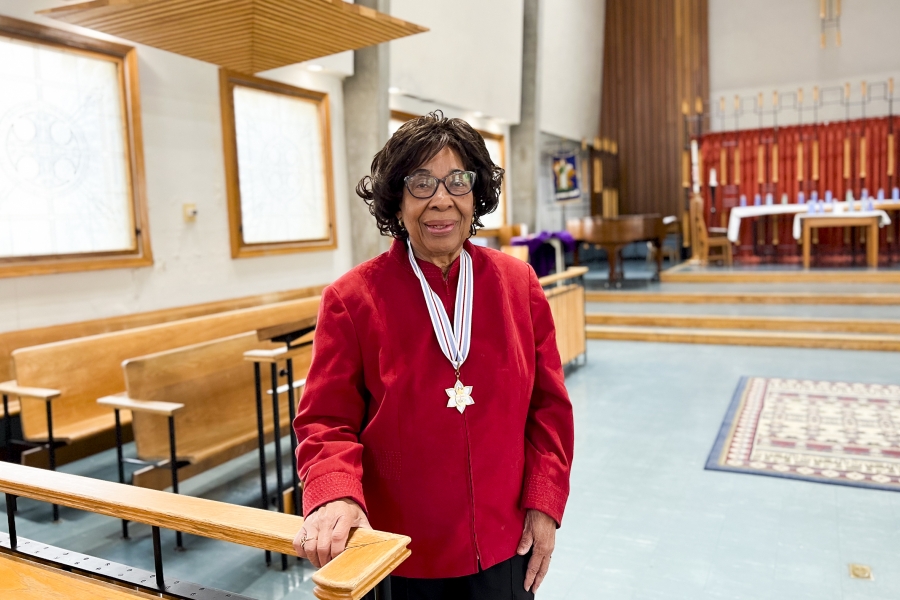 Dr. June Marion James standing in a chapel wearing a red sweater