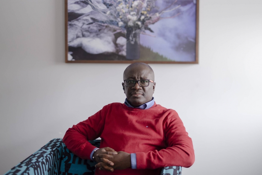 Edmund Opoku-Agyeman sitting in a chair wearing a red crewneck
