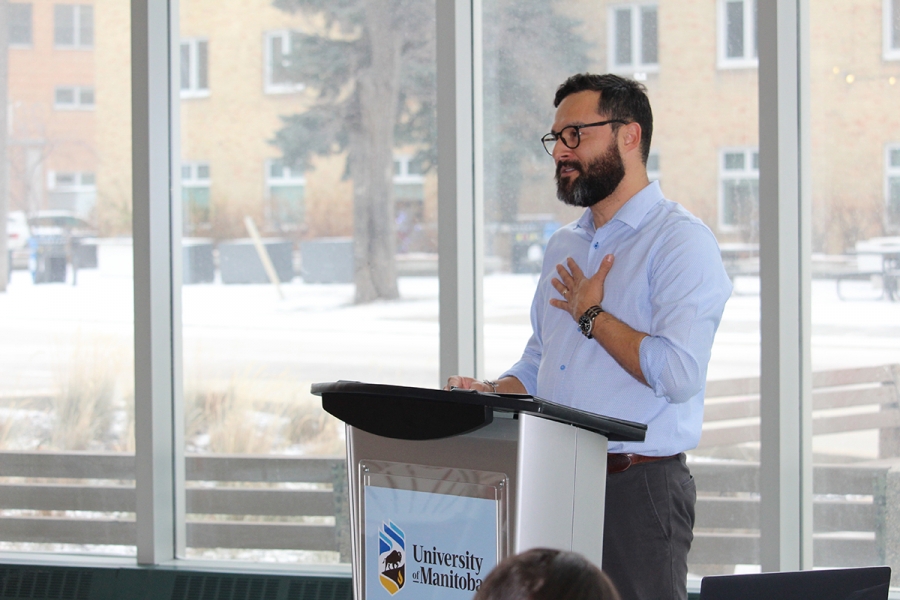 Edgar French speaks at a podium in front of a large window at Bannatyne campus.