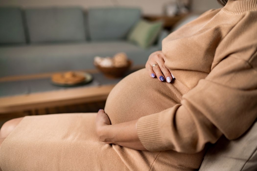 A pregnant person holds their belly. 