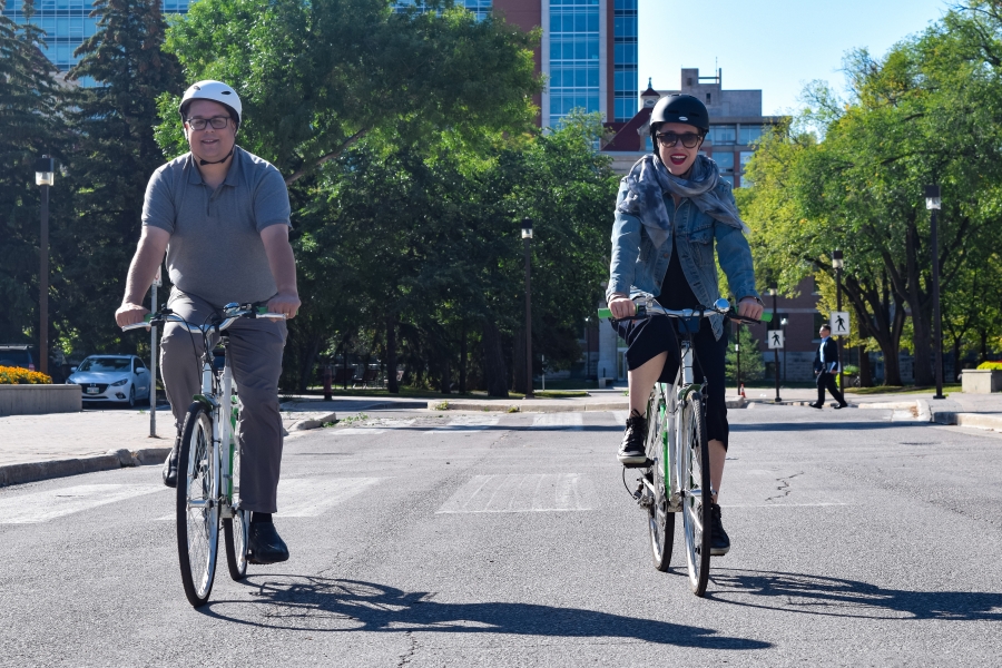 Two people enjoying Fort Garry campus by bike.