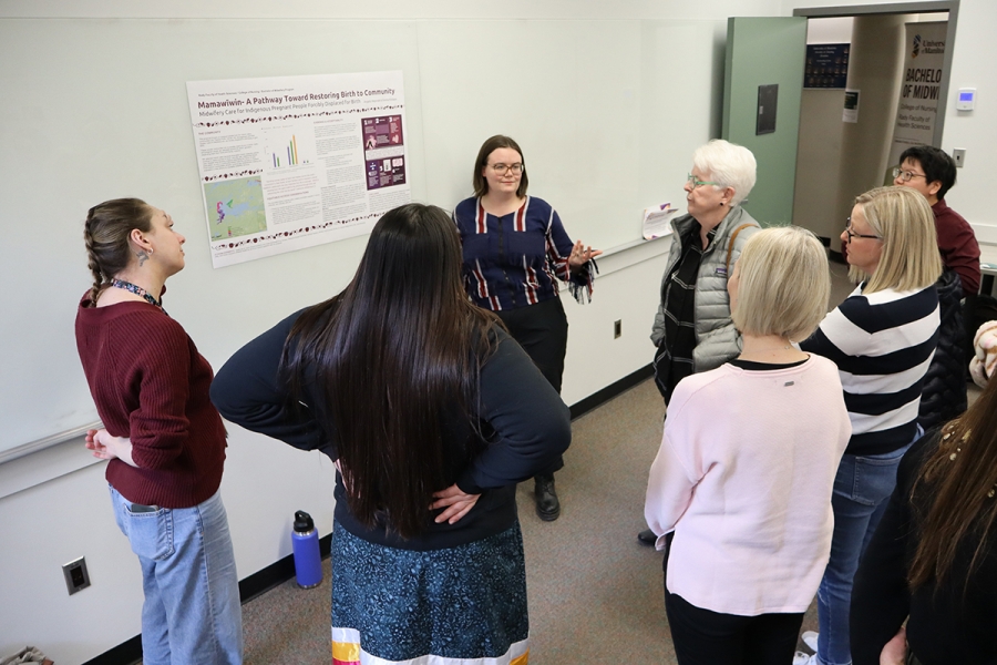 A student explains her poster project to a group of people.
