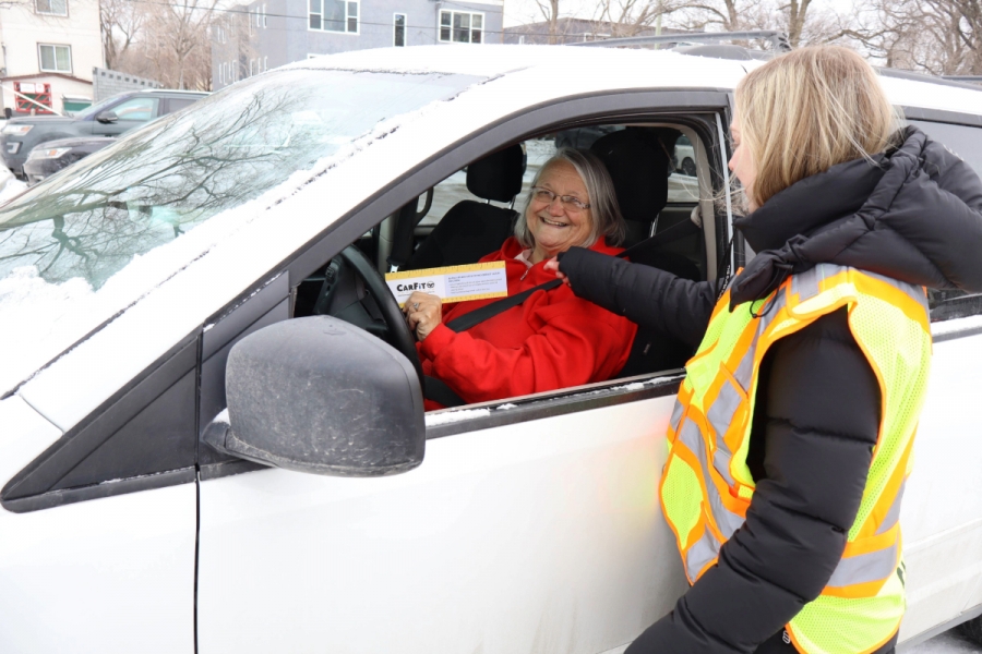 A student volunteer does safety measurements with an older driver in her car.