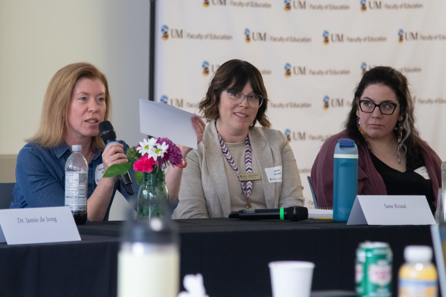 Three panelists are sitting at the table while one is sharing her insight with the audience