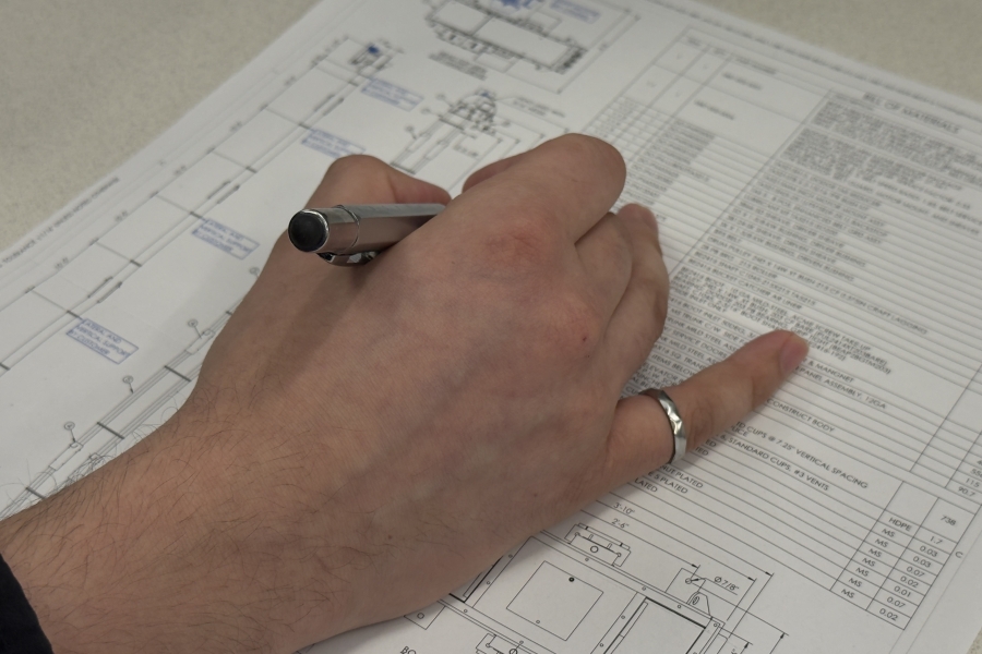 A hand writing on paper with iron ring on pinky finger clearly visible