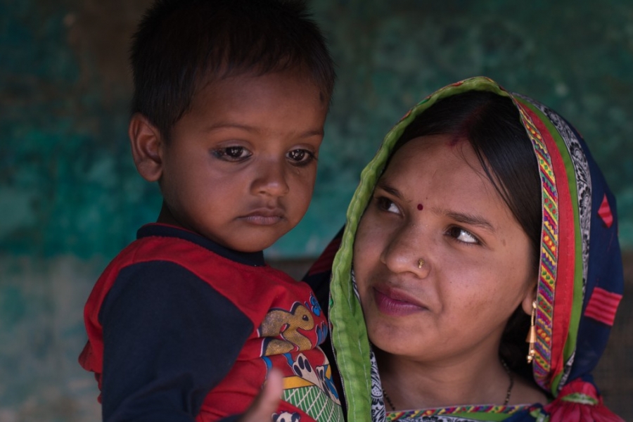 A toddler is pictured while the mother holds and looks at the child.