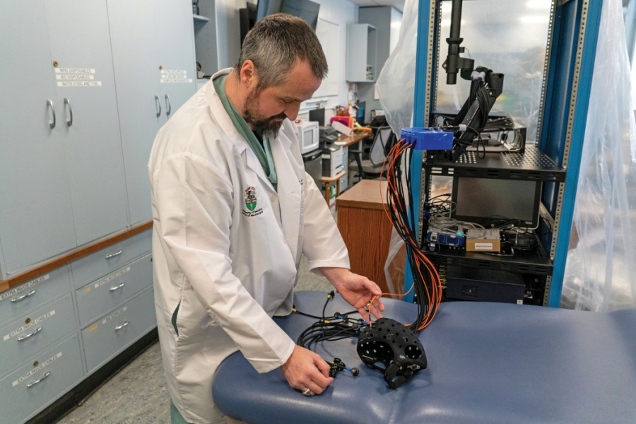A researcher in his lab works with a monitoring device that is connected to several wires.