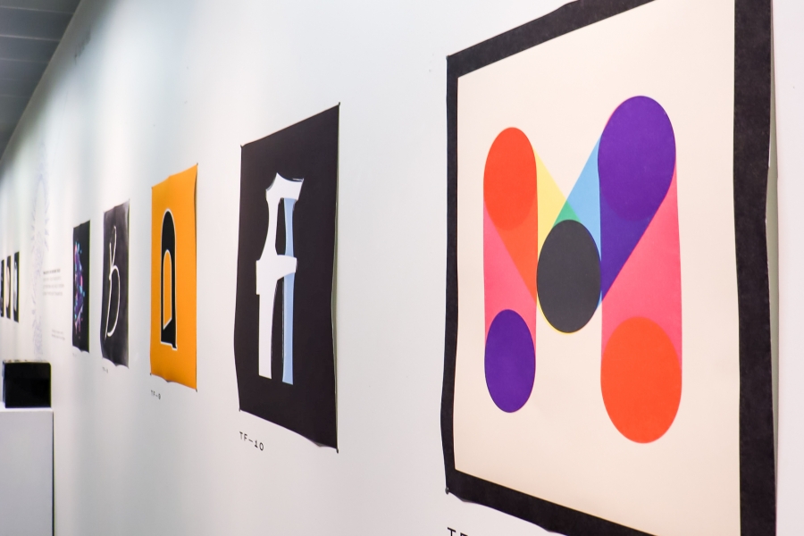 Wall display of student-designed type posters, featuring Malia Davis’s winning TypeFight 2025 submission with bold overlapping geometric shapes.