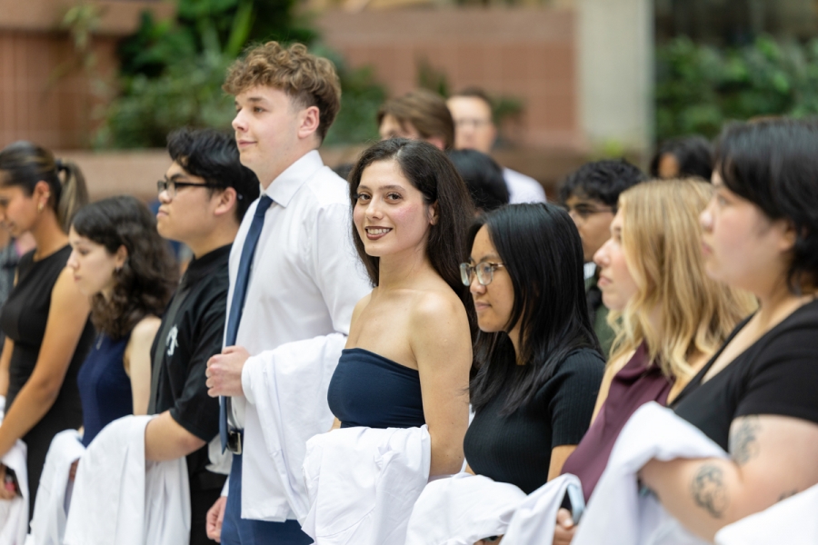 A group of students standing together with white coats draped over their arms.