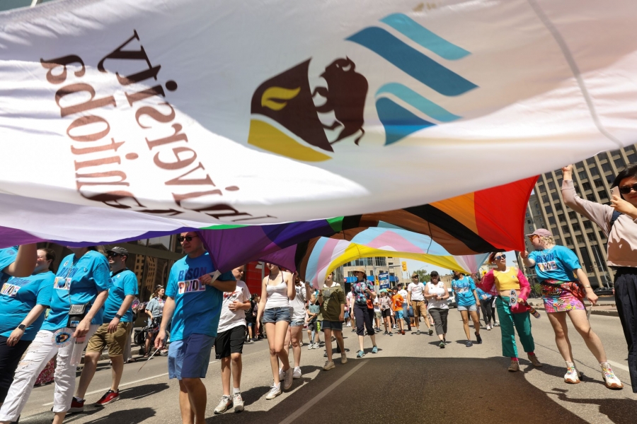 UM community members walking in Pride Winnipeg Parade, carrying banners and signs.