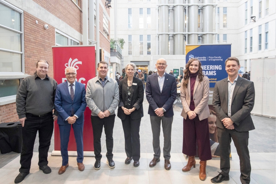 A group of people posing in front of institutional banners in a bright indoor space