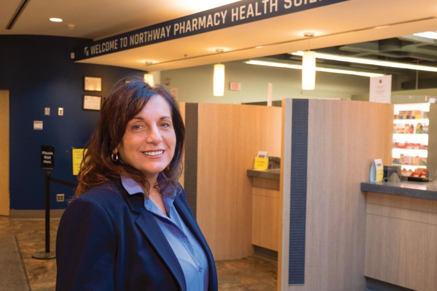 A person smiling at the camera inside a pharmacy.