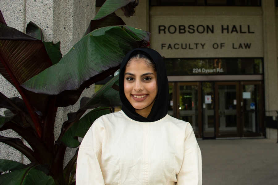Internationally trained law student Sofia Shoukat stands in front of a large leafy plant in front of Robson Hall