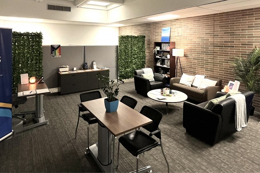 Wide view of cozy open room with sofas, table and chairs, and sign that says Student Wellness Centre.