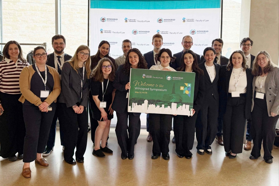 a group of happy students hold a sign for the Winograd Symposium