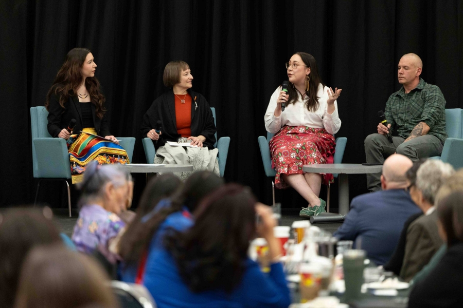 Four panelists engaged in discussion on a stage.