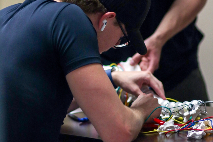 A student works on a model of a spine with electrical wires.