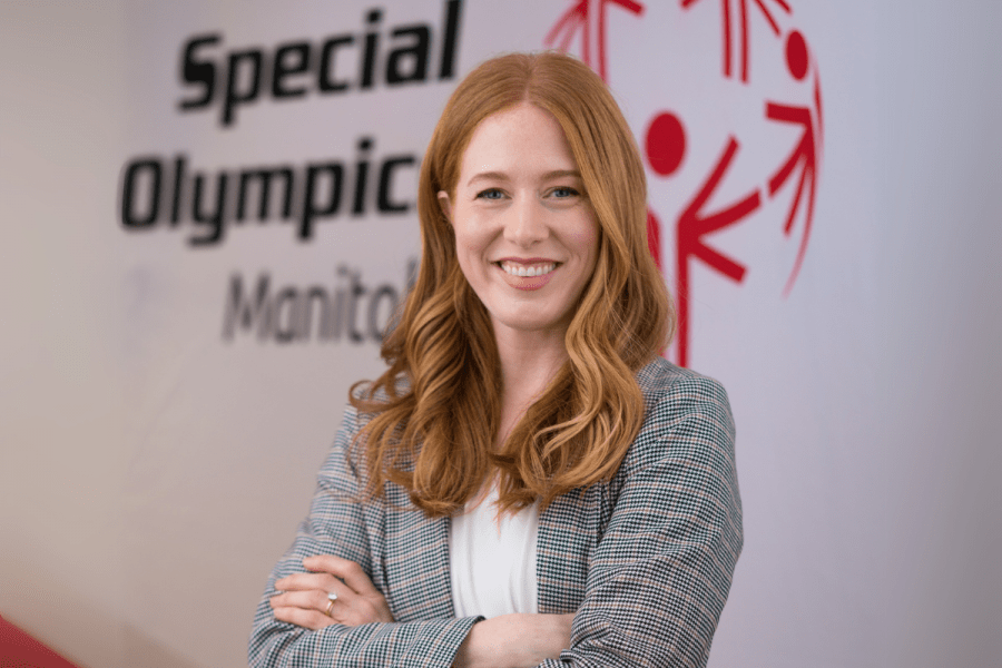 Rachel Whetley poses in front of a sign for Special Olympics Manitoba