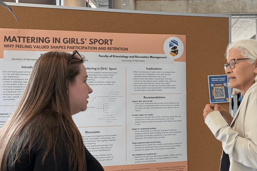 A student talks to a professor about their poster at Research Day 2026.