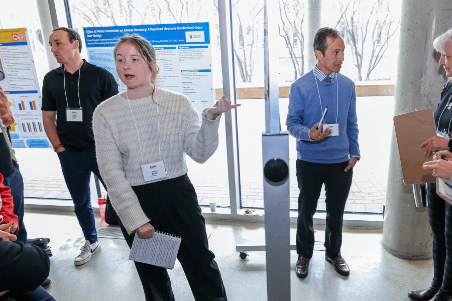 Students explain their posters to participants at Research Day.