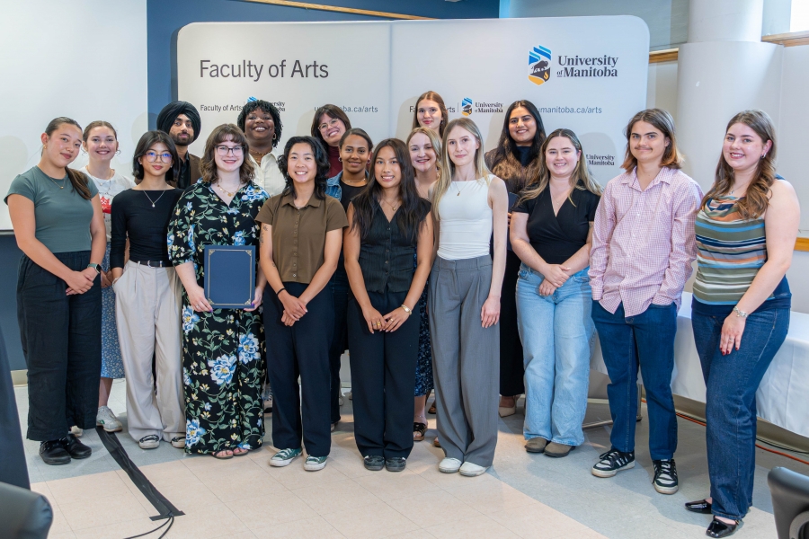 A group of over 20 students posing in front of the Faculty of Arts banner.