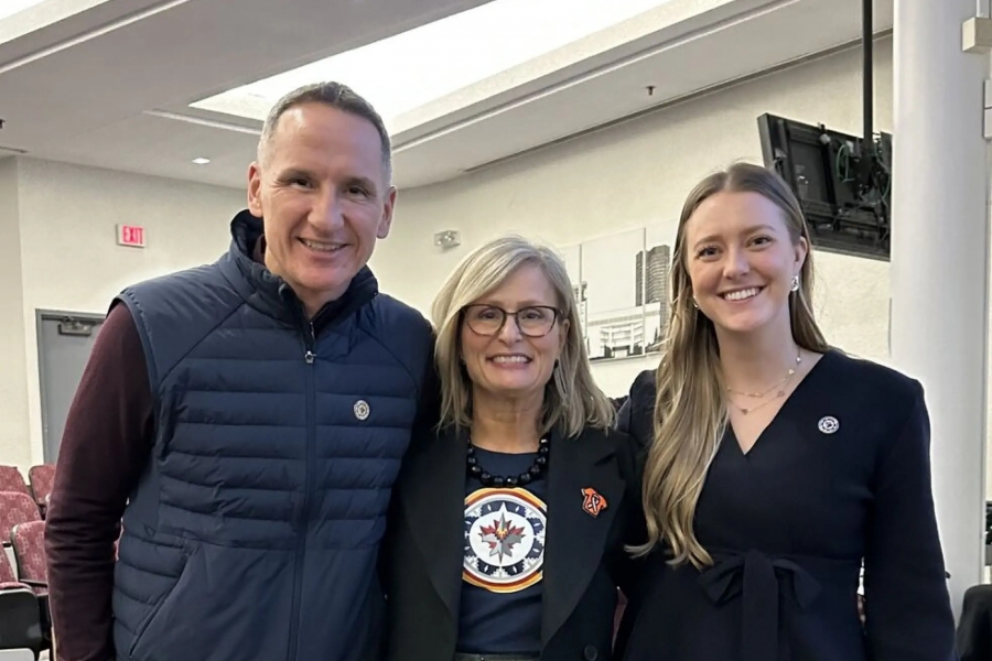 Two women and a man standing in a classroom.