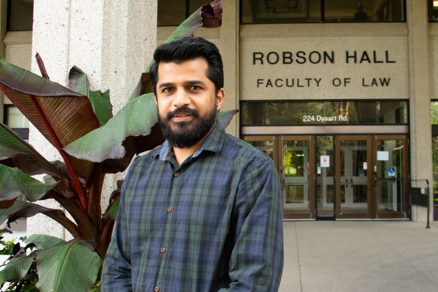 Waseem Ahmed in a blue and green plaid shirt in front of Robson Hall Faculty of Law