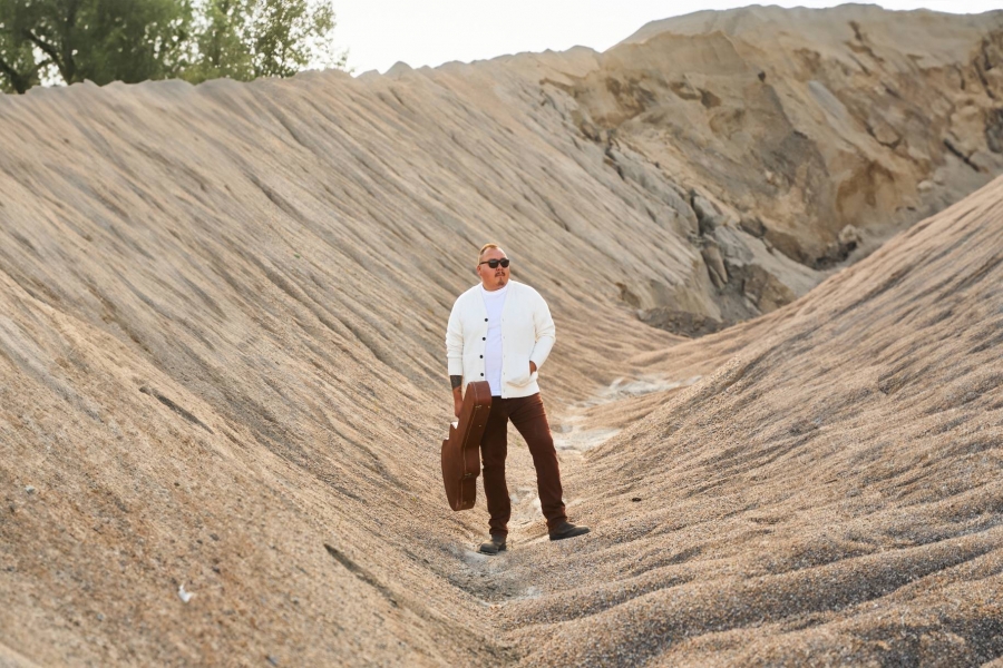 William Prince standing between two sandy hills.