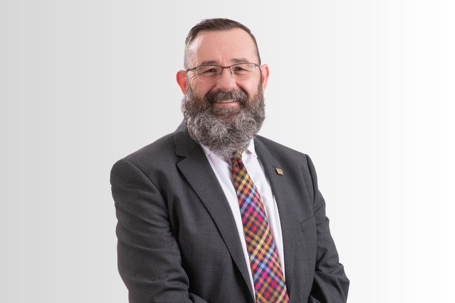 A person with a grey beard and a bright tie. 