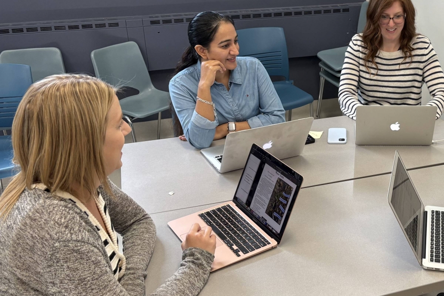 three students sitting at table with laptops