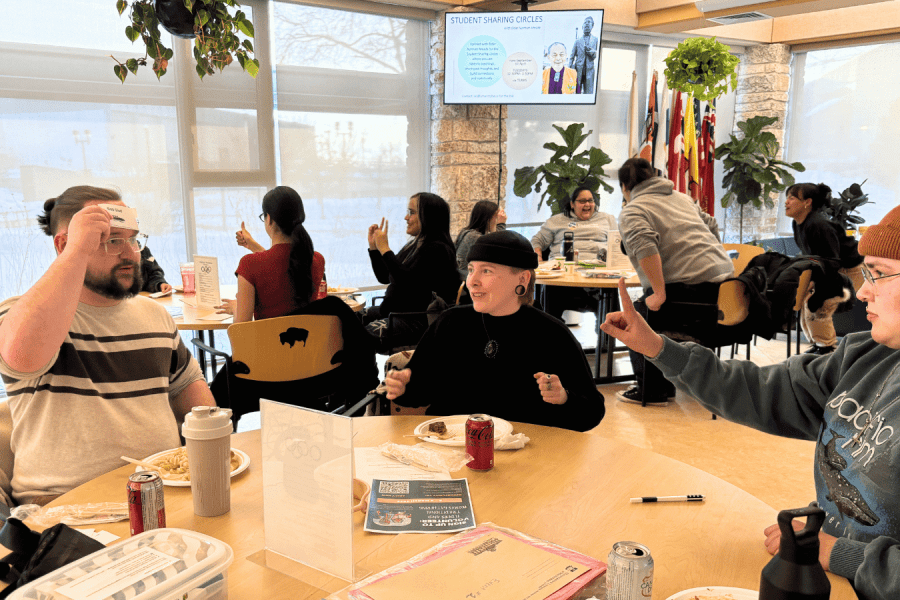 Students gather around tables during a Blankstein Momentum Program sharing circle, talking, eating and participating in a group activity.