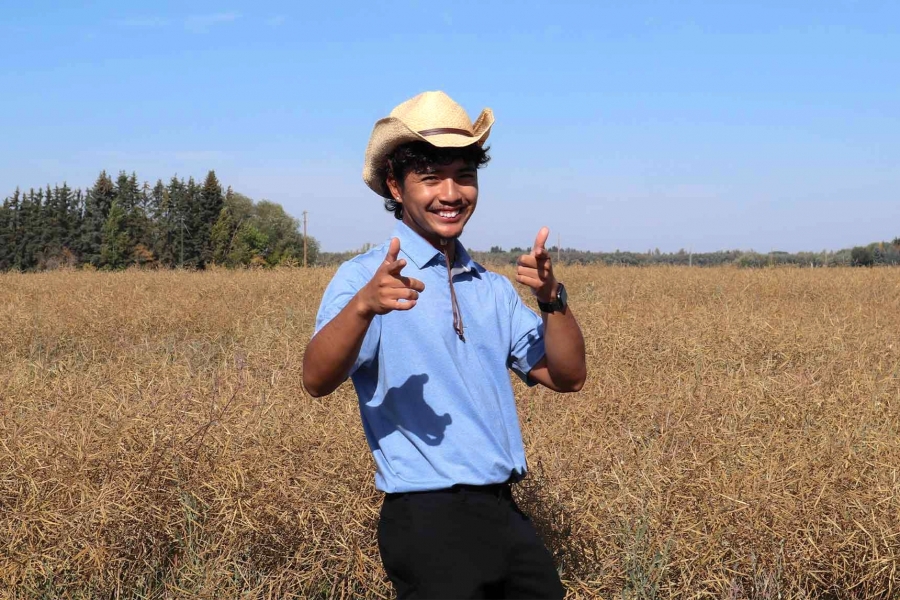 Brigo wearing a blue collared shirt with a hat smiling at the camera.