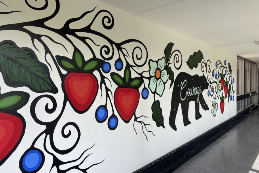 mural with strawberries, leaves and blueberries with a black bear painted on white wall.