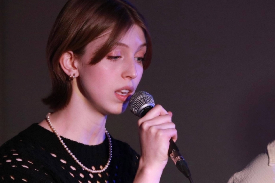 Emma Lewis sings into a microphone.
