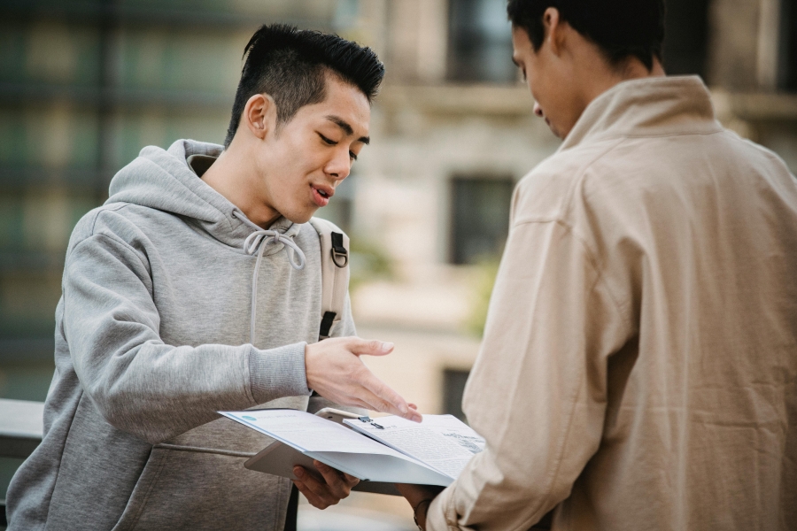Two students standing and discussing notes in a binder