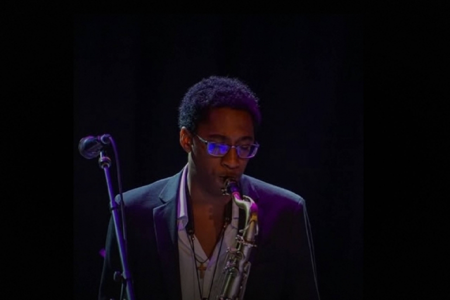 Samuel Murell-Cole plays saxophone next to a microphone. 
