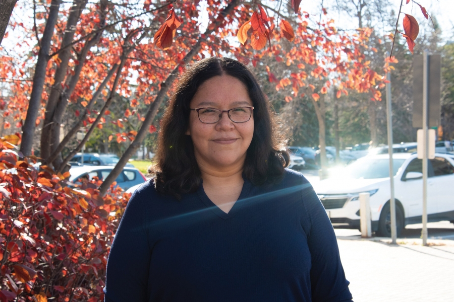 Shana wearing a blue long sleeves in front of a tree smiling at the camera.