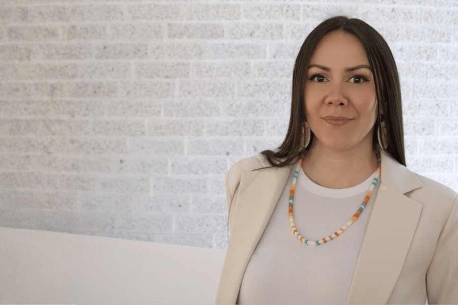 A woman with long dark hair, wearing colourful beaded earrings and a matching necklace.