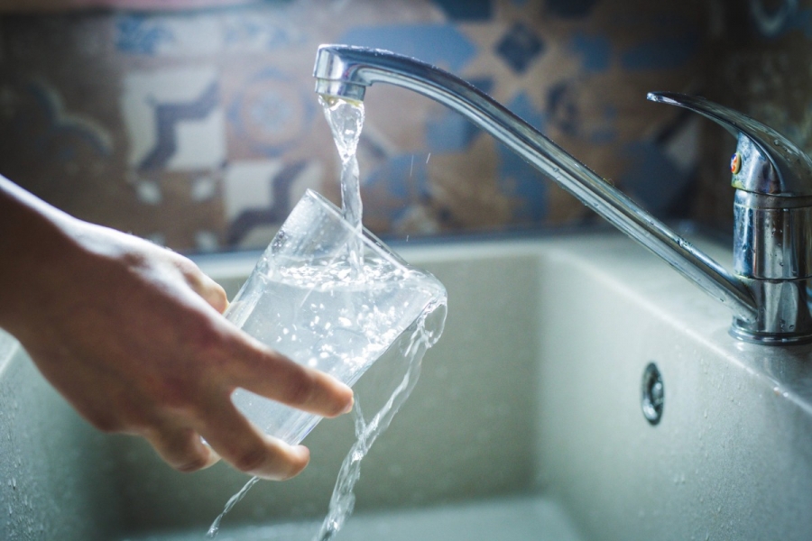 Drinking water in the sink pours in glass.